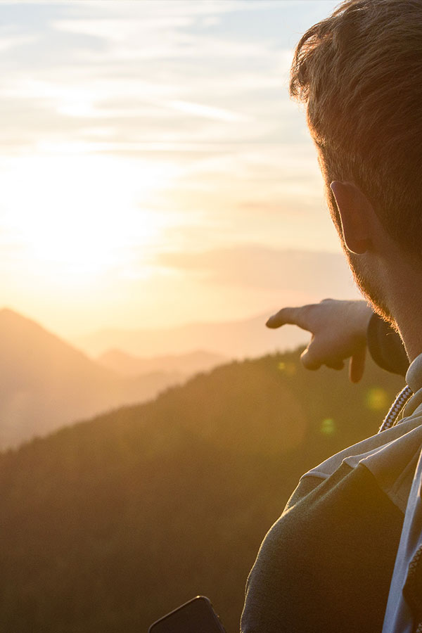 Sonnenuntergang über den Allgäuer Bergen – Erholung nach dem Canyoning Person zeigt auf Sonnenuntergang in den Allgäuer Alpen – Ausblick nach Canyoningtour im Oberallgäu